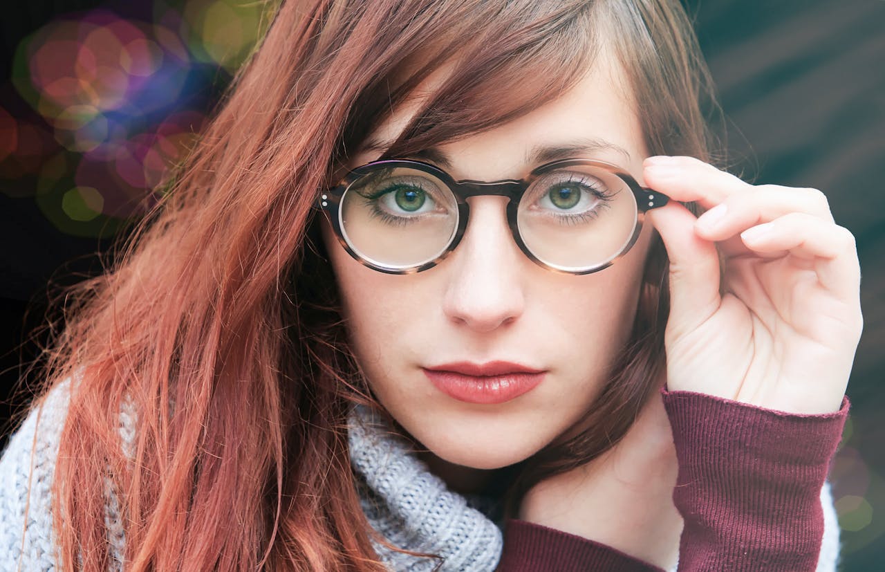 Close-up portrait of a woman with glasses, offering a stylish and thoughtful look.